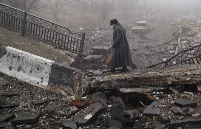 640x410_an-elderly-woman-walks-across-a-destroyed-bridge-fallen-onto-the-road-towards-the-airport-the-scene