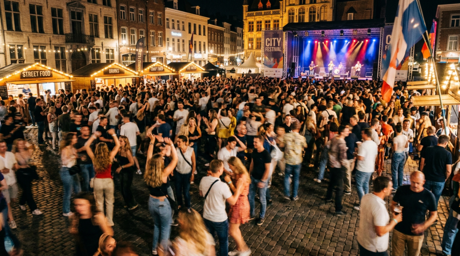 Large crowd at night festival with live band on stage and food stalls